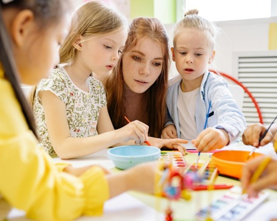 Teacher guiding children during a collaborative classroom activity.