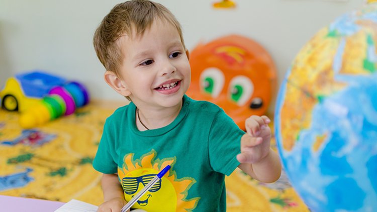 Child exploring a globe during classroom learning.