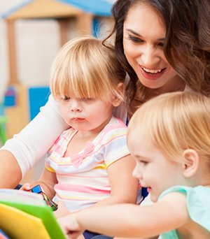 Caregiver reading with young children during classroom time.