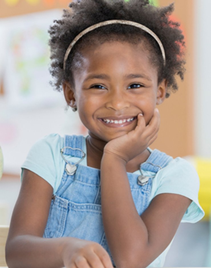 Child smiling in a welcoming daycare classroom.