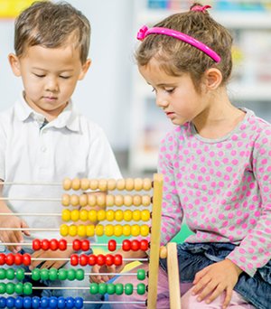 Toddlers exploring counting beads during guided learning.