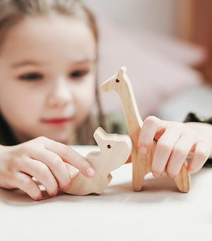 Child using wooden animals during imaginative play.
