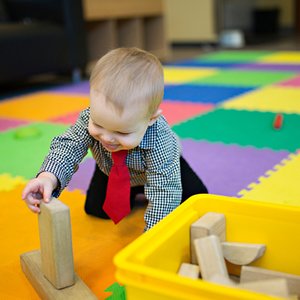 Infant exploring blocks during supervised floor play.