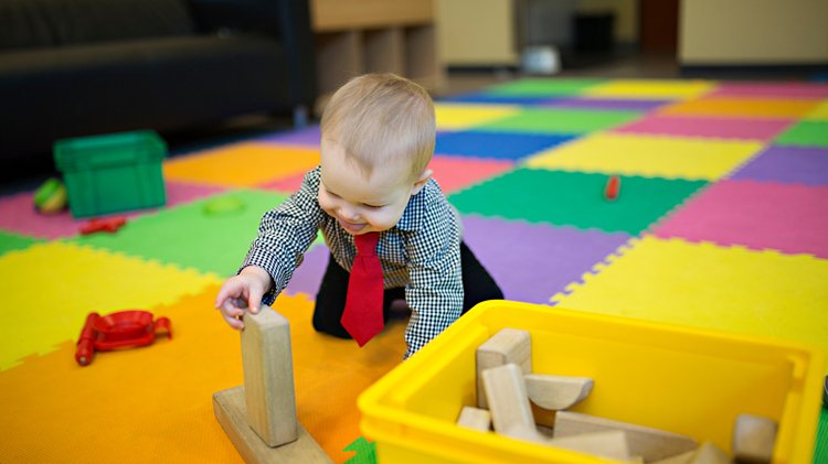 Infant exploring blocks during supervised play.